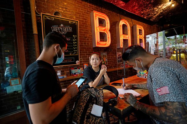 Server, left, takes a drink order from Jasmine Lao, left, as her friend Matthew Alcon fills out his contact information at e's BAR on the Upper West Side, May 17th, 2021